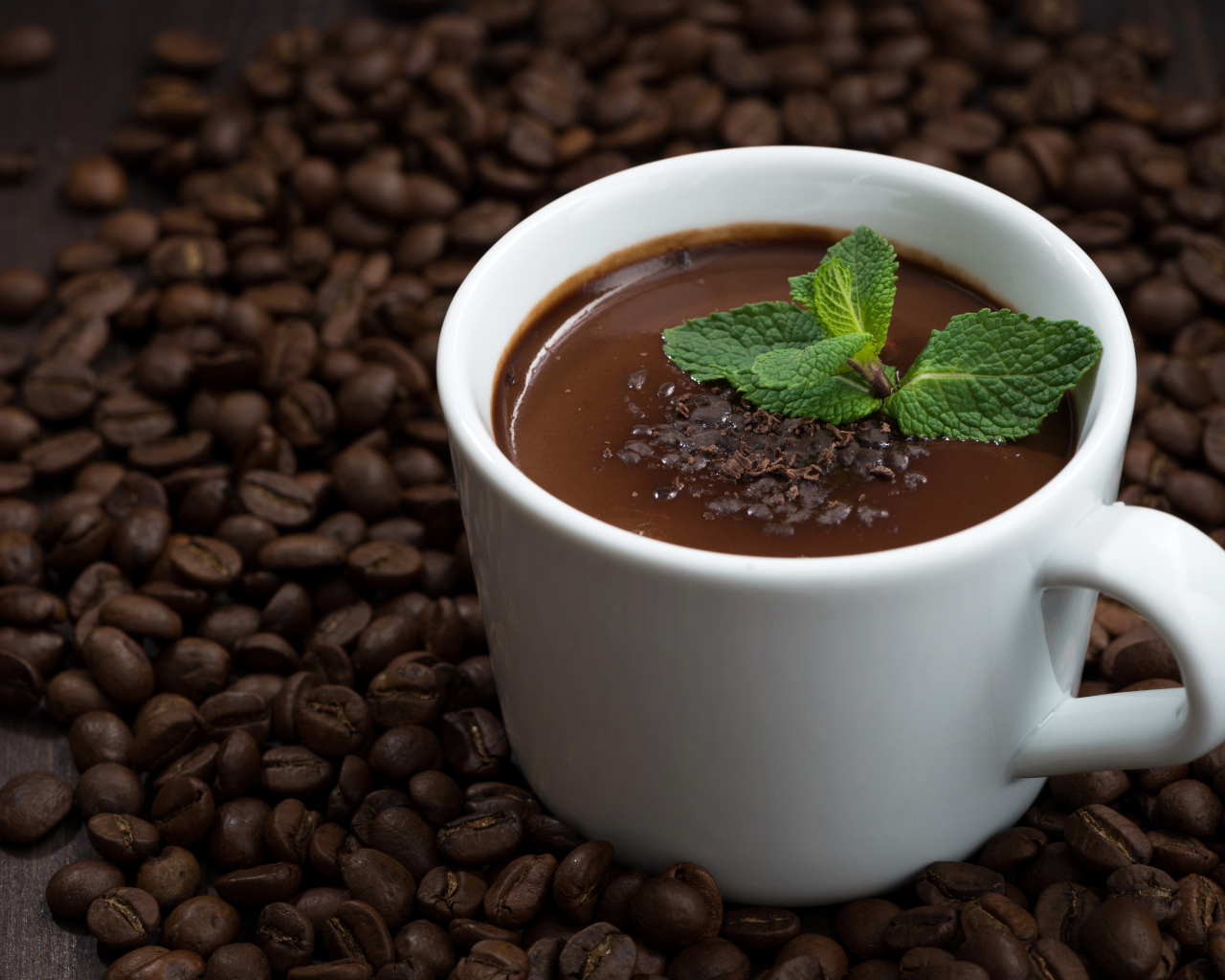 Белая чашка горячего шоколада стоит на кофейных зернах