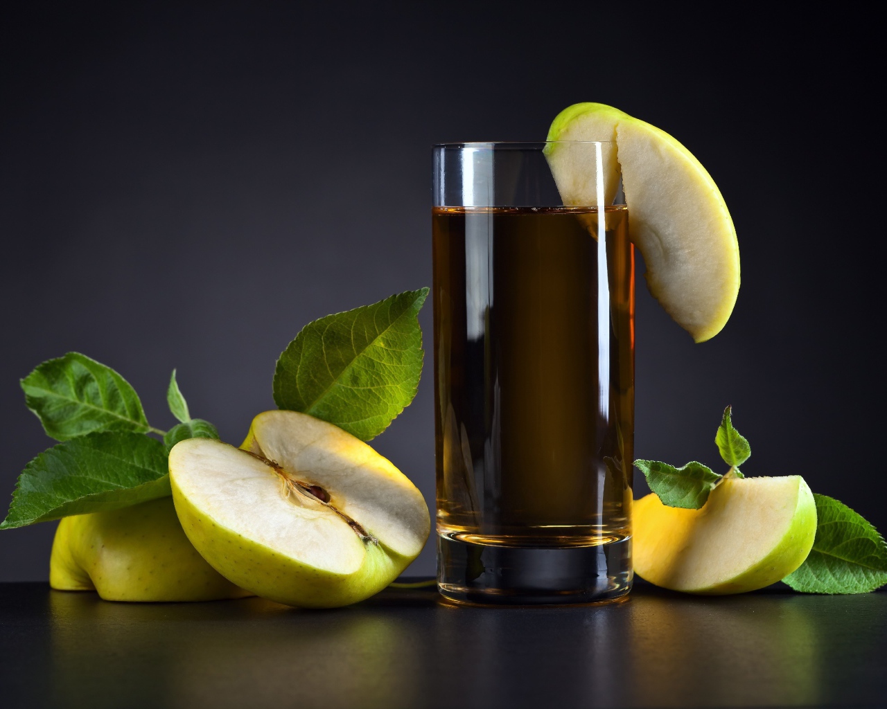 Яблочный сок в стакане на столе со свежими яблоками на сером фоне