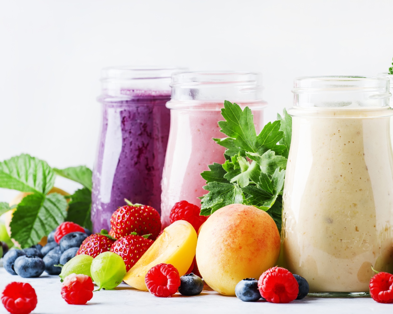 Ягодные смузи в бутылочках на столе с ягодами