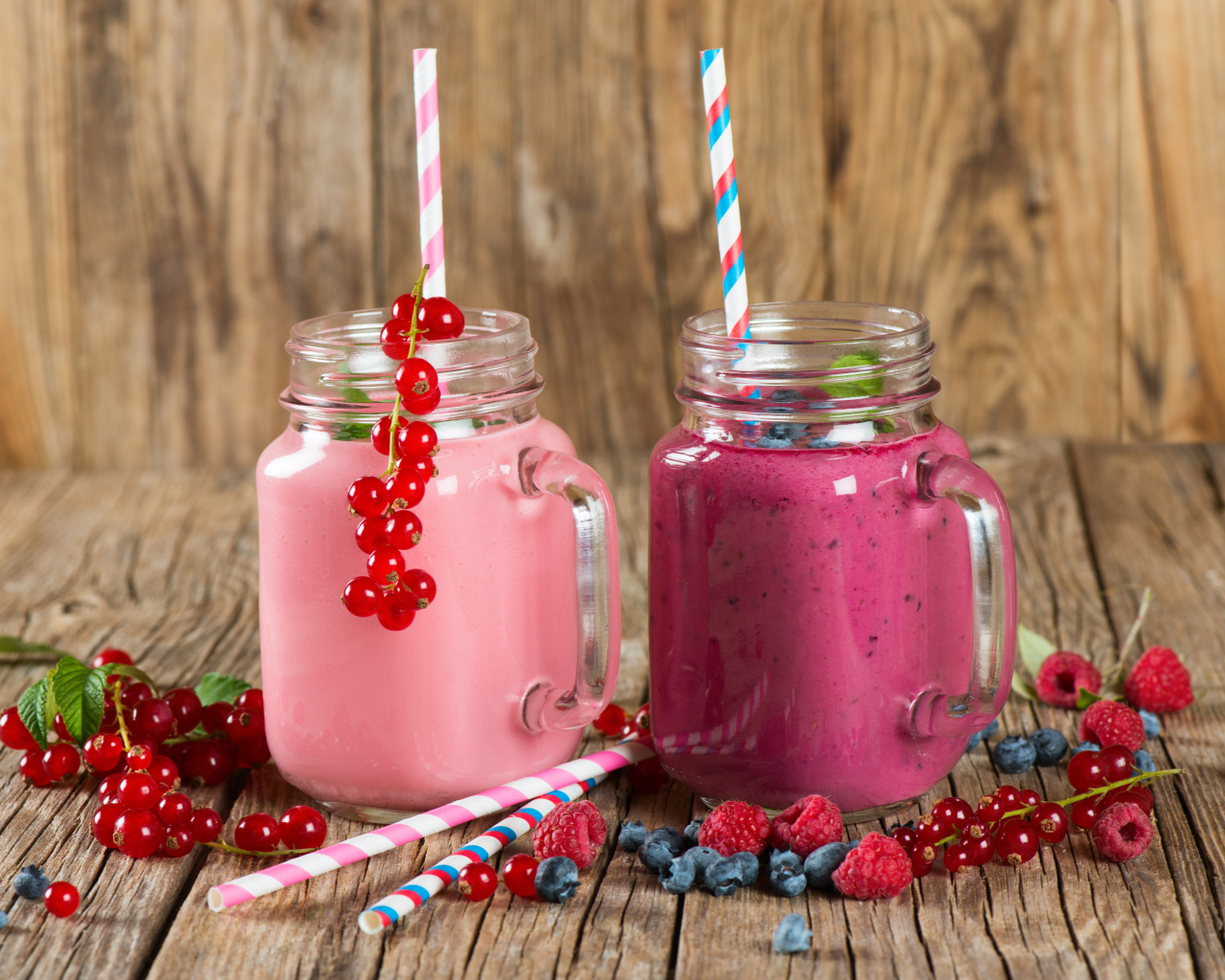 Ягодное смузи в баночках на столе со свежими ягодами малины, смородины и черники