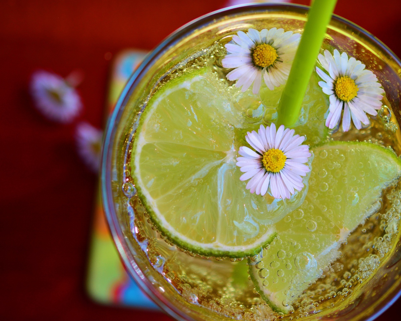 Газированный напиток с кусочками лайма и ромашками в стакане 