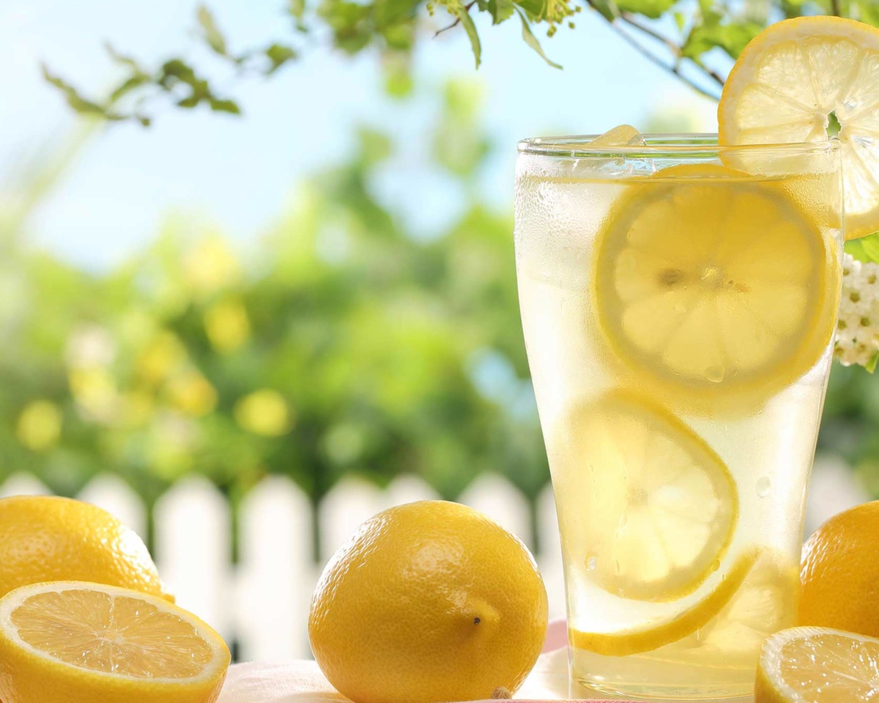 Холодный лимонад в стакане с кусочками лимона