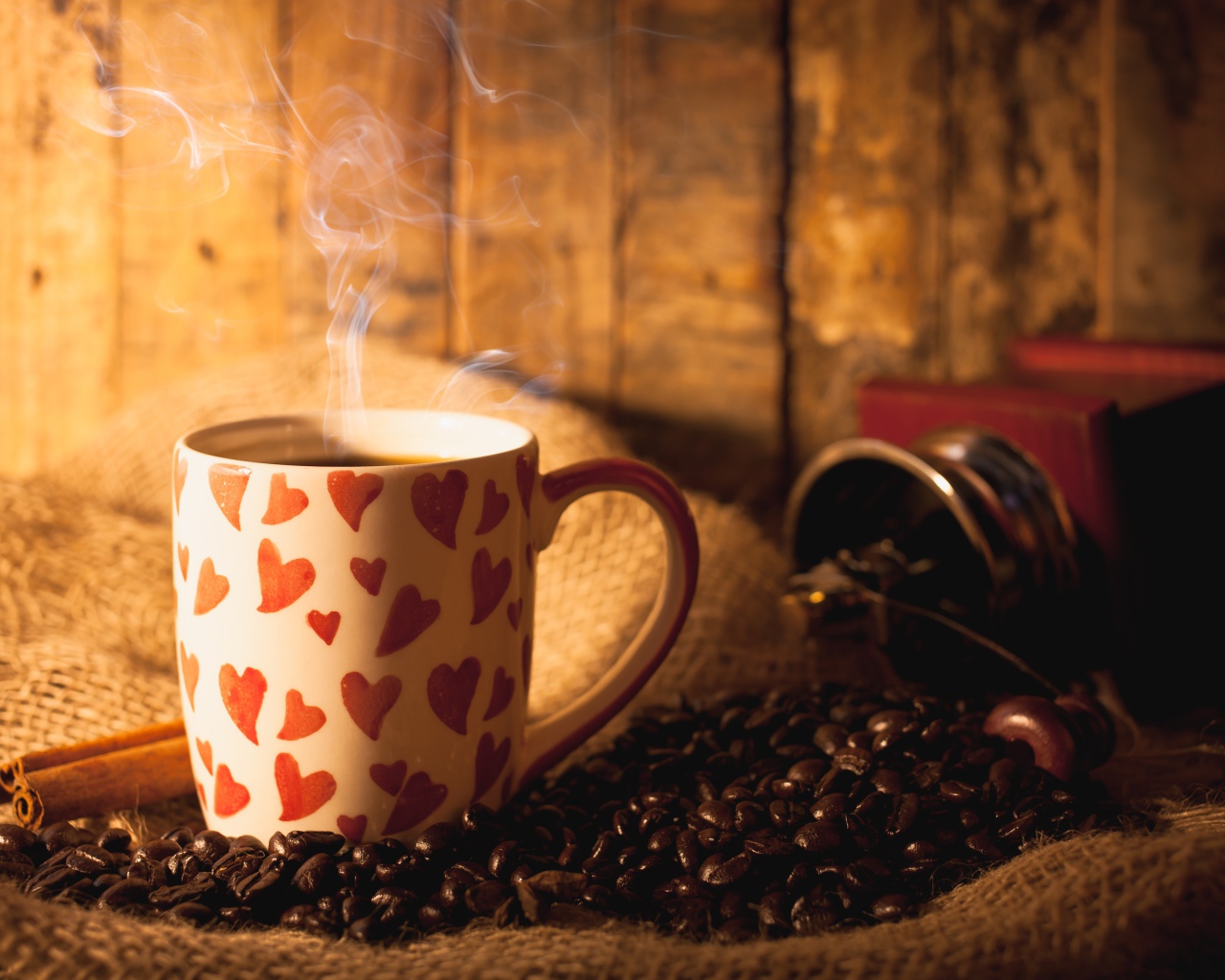 Чашка с горячим кофе на столе с кофейными зернами и корицей