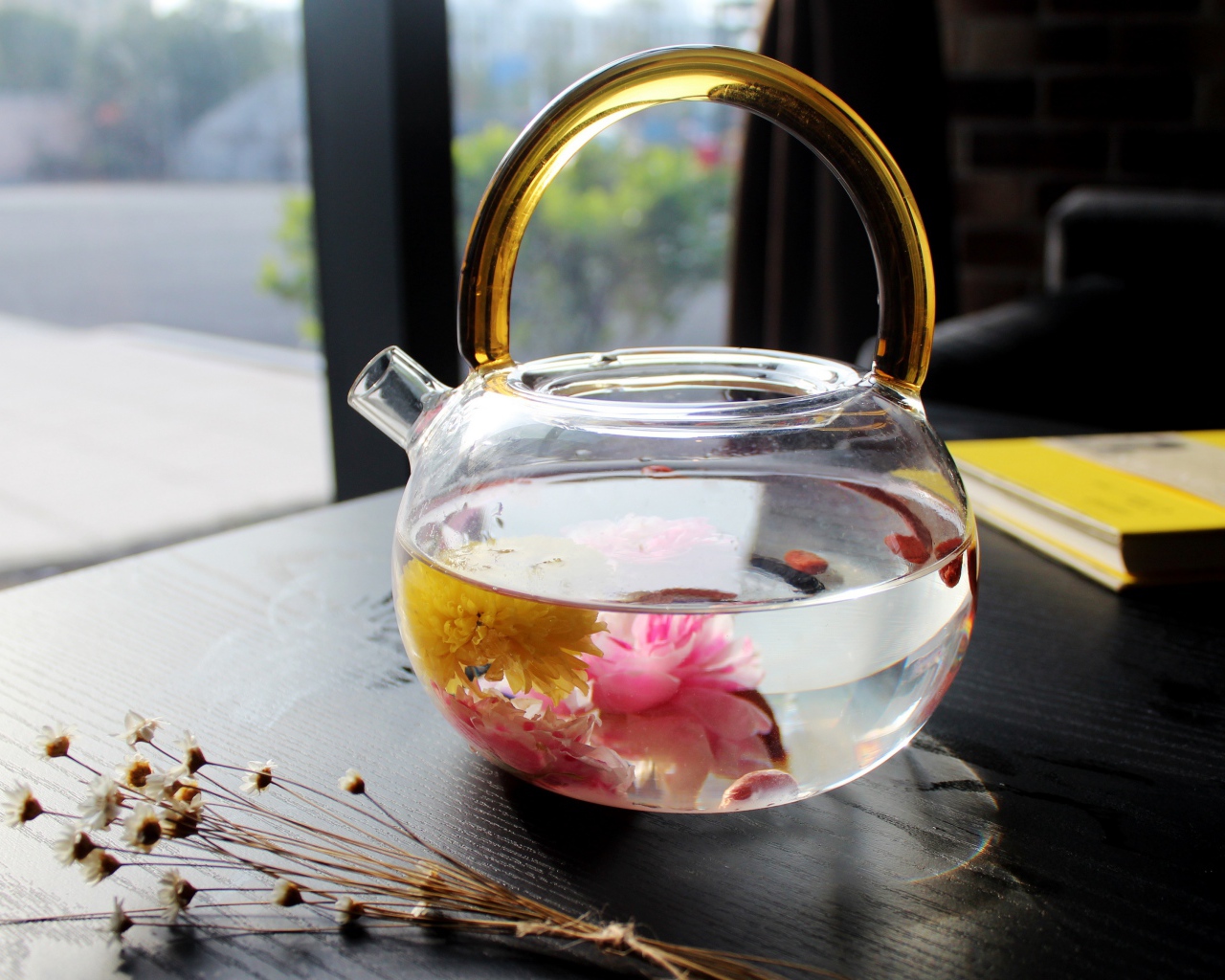 Цветочный чай в стеклянном чайнике на столе 