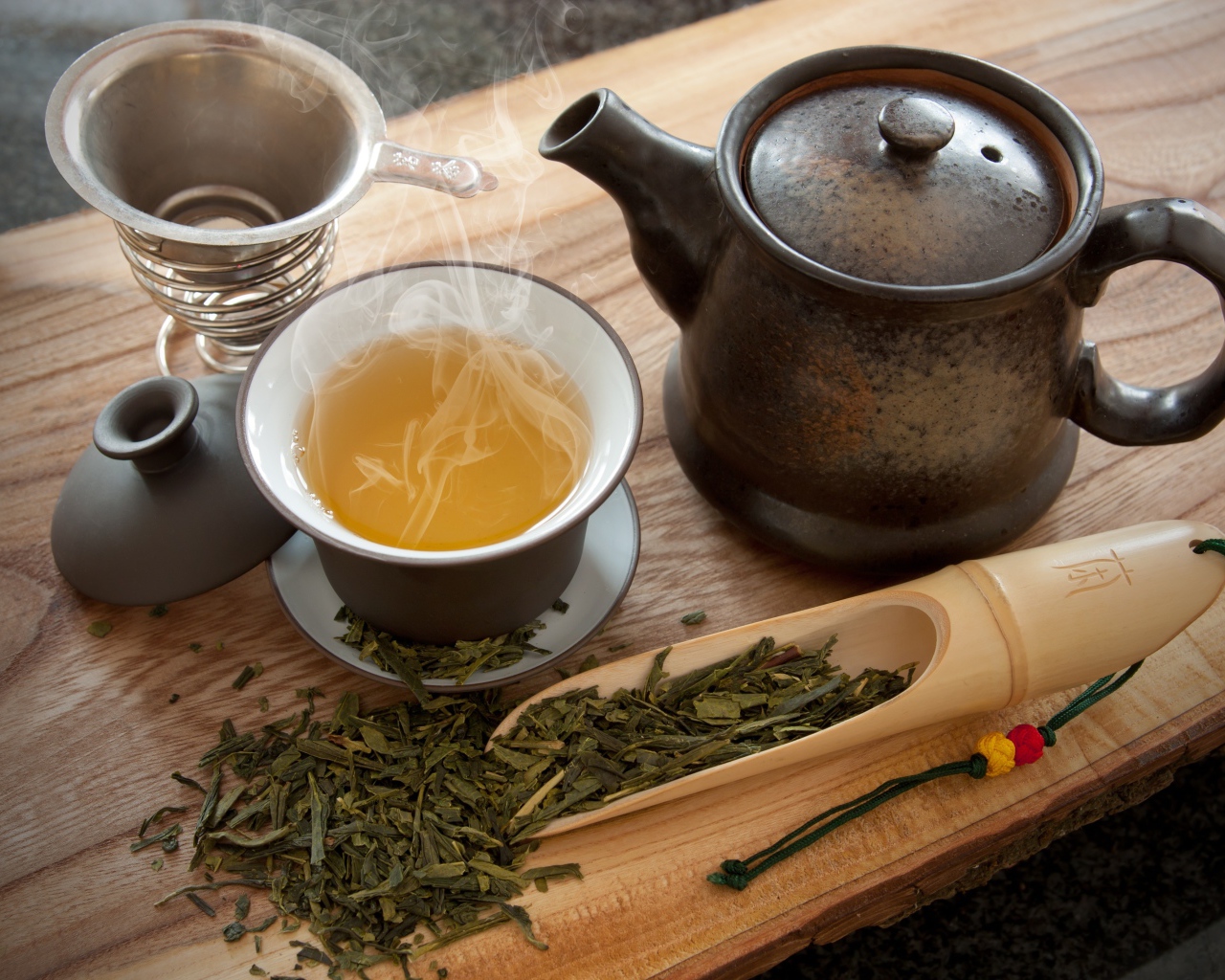 Свежий горячий чай на столе с чайными листьями и чайником