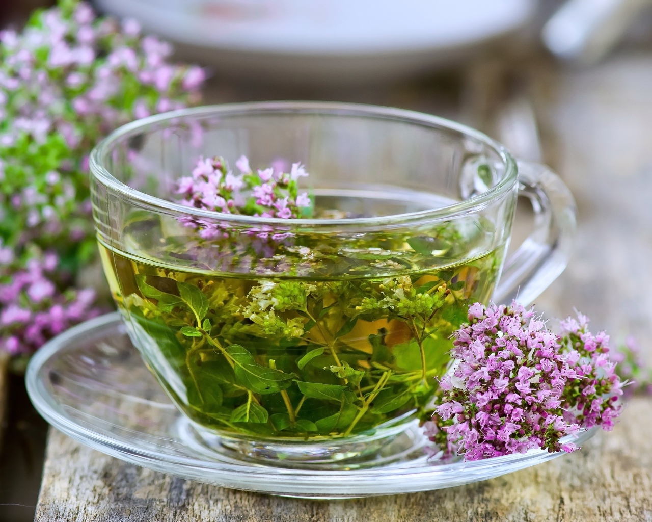 Стеклянная чашка зеленого чая с цветами чабреца