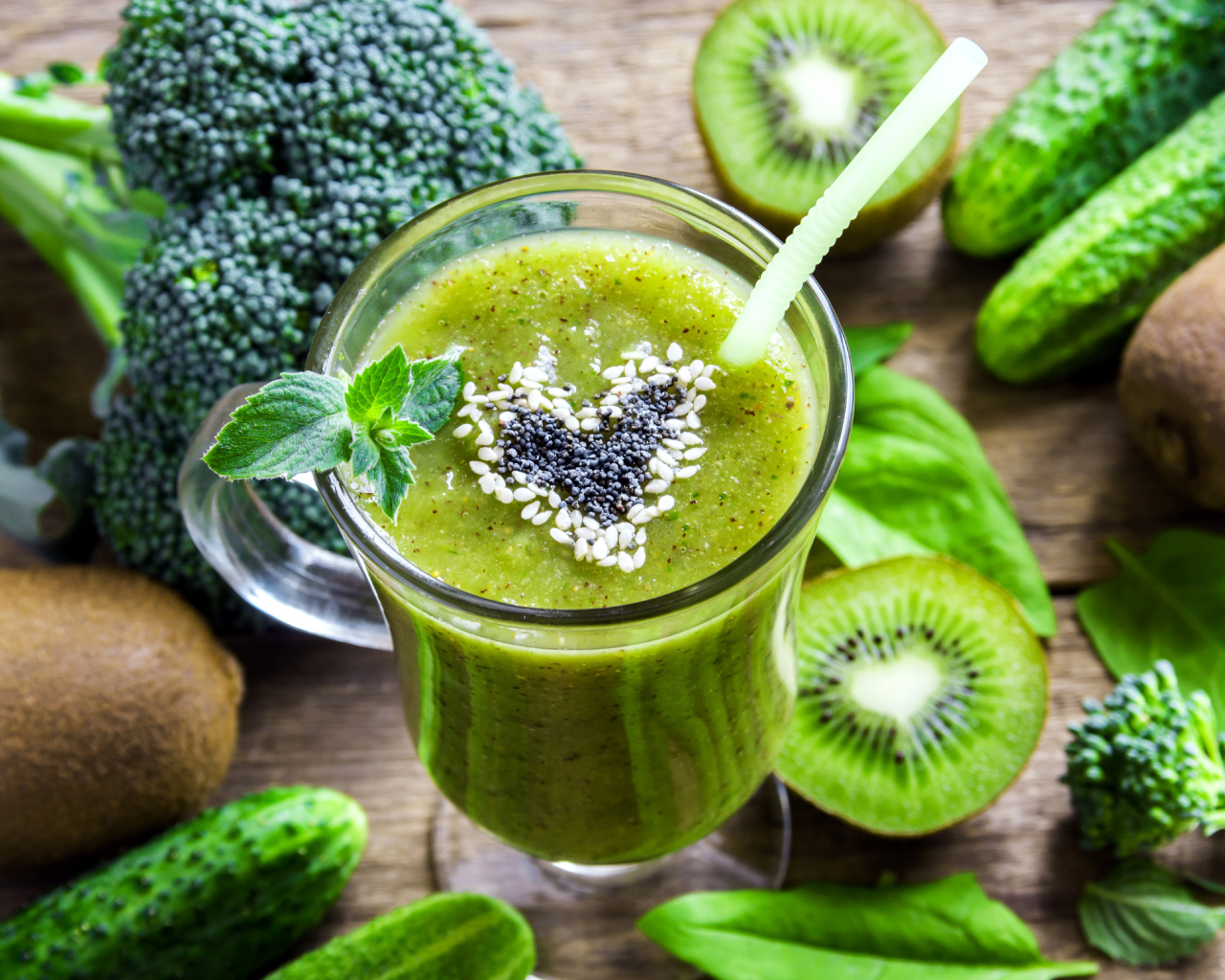 Стакан зеленого смузи на столе с киви, огурцами и брокколи