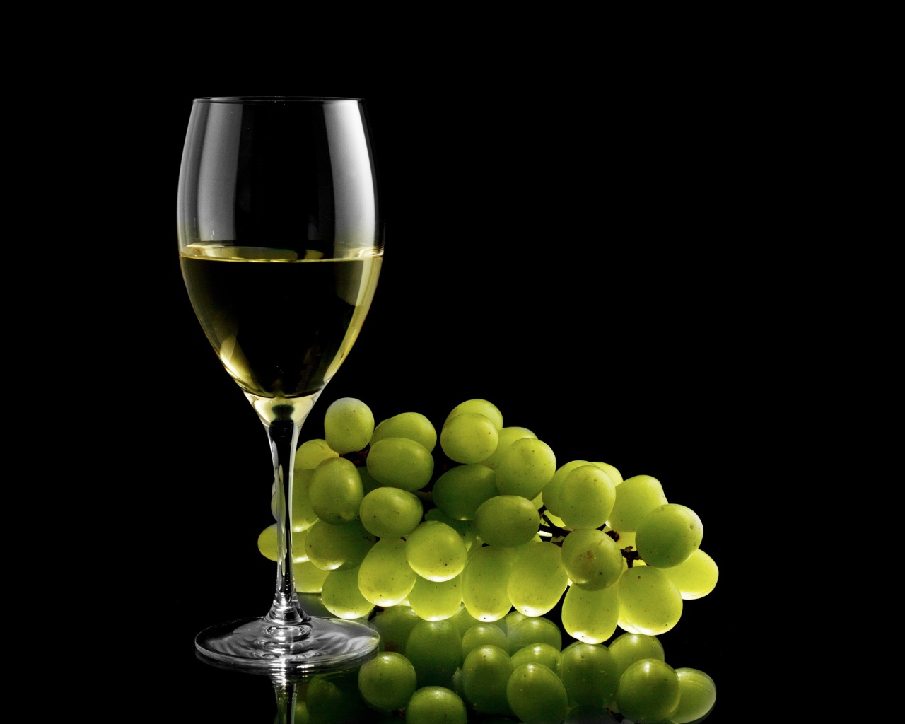 Бокал белого вина с белым виноградом на черном фоне