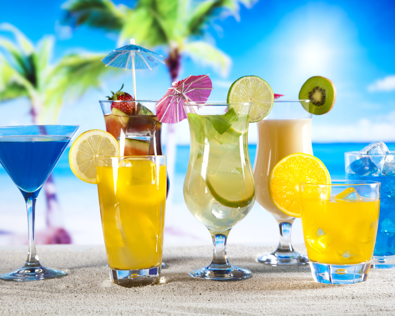Бокалы с тропическими коктейлями на песке на пляже
