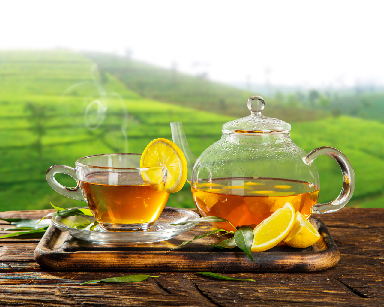 Зеленый чай с лимоном с стеклянной чашке на столе