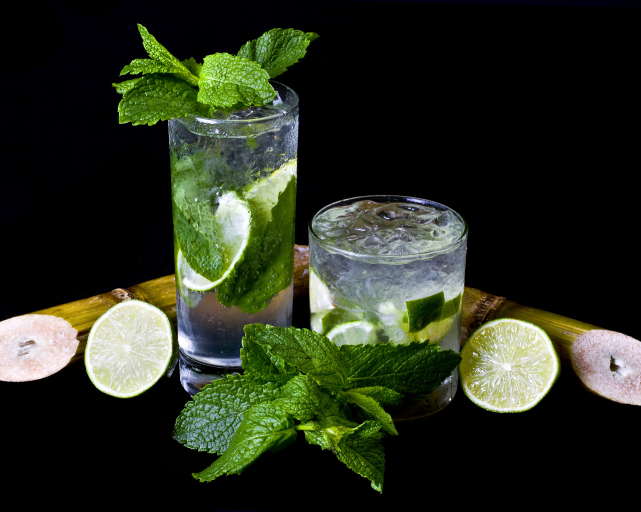 Напиток мохито в стаканах с лаймом и листьями мяты на черном фоне