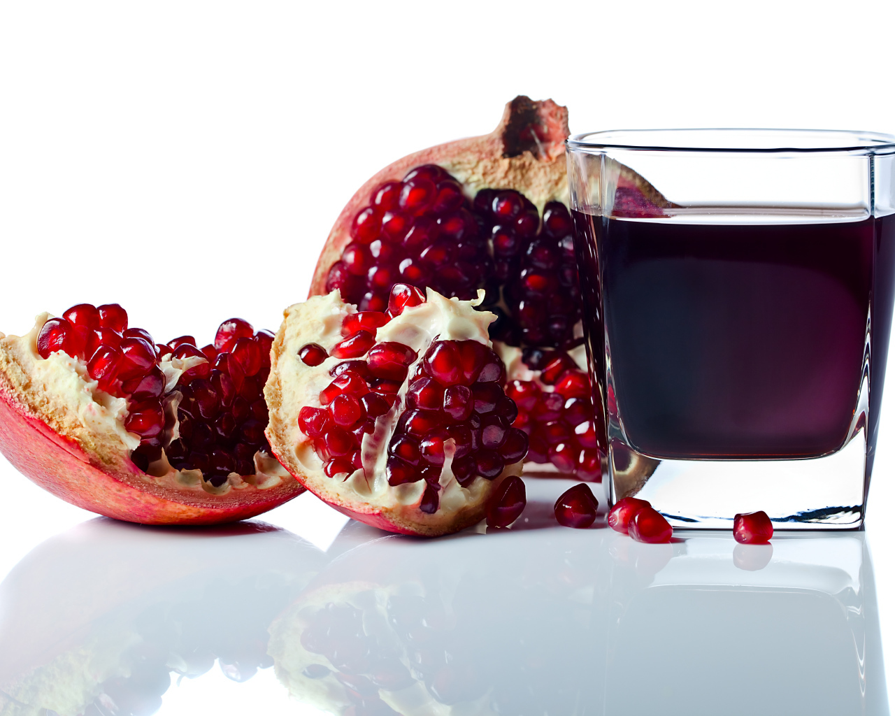 Гранатовый сок с плодом граната на белом фоне