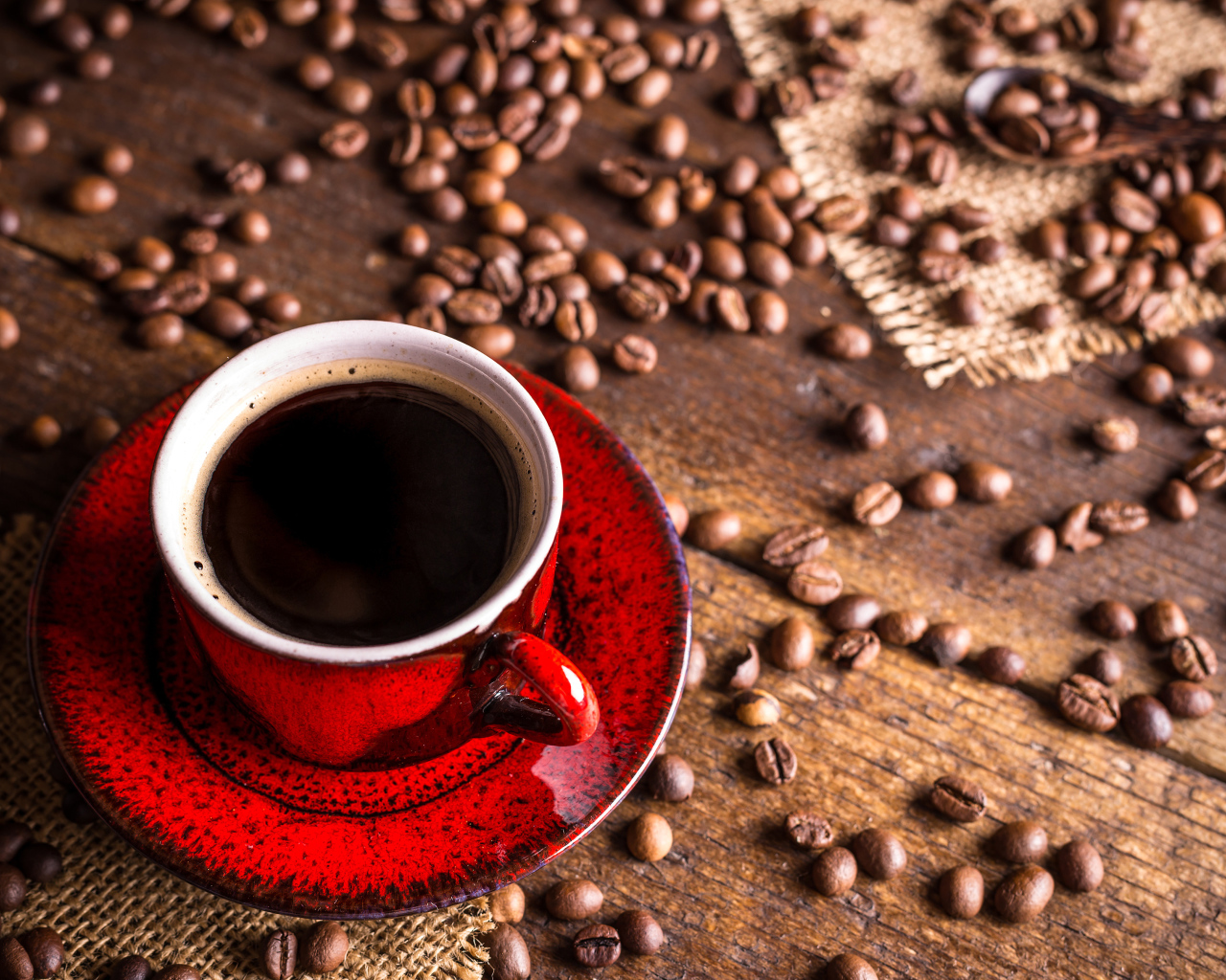Красная чашка кофе на столе с зернами кофе