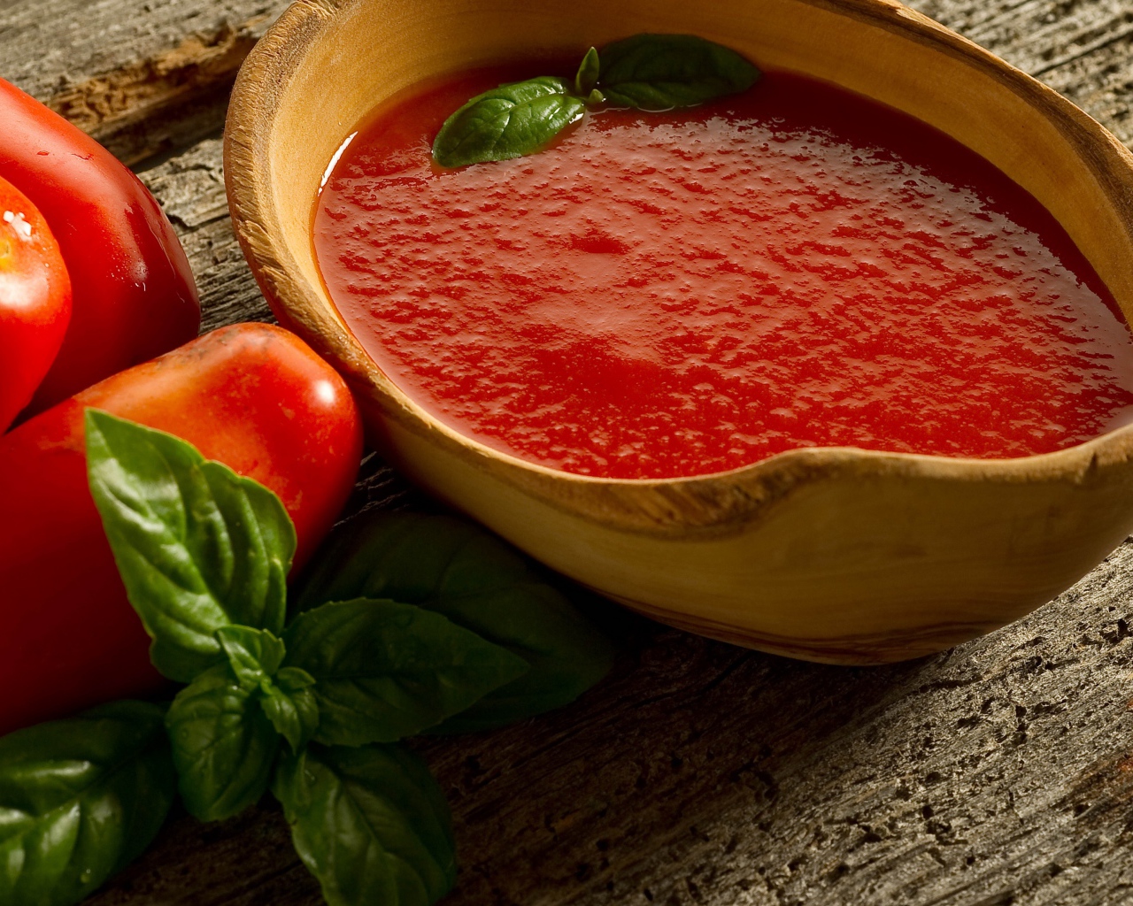 Томатный сок в деревянной посуде на столе с помидорами и базиликом