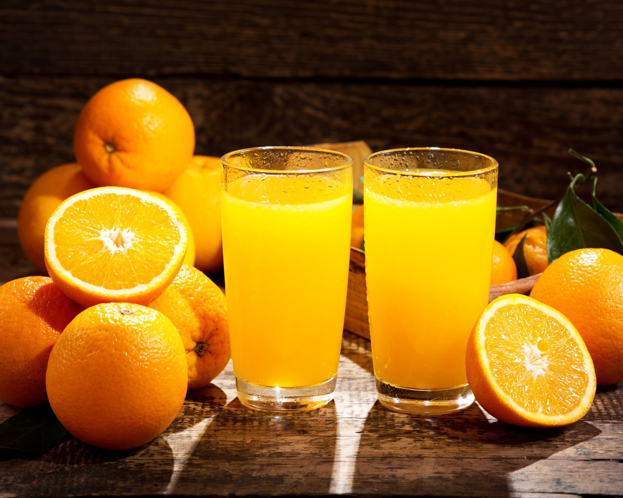 Два стакана свежего апельсинового сока на столе с фруктами