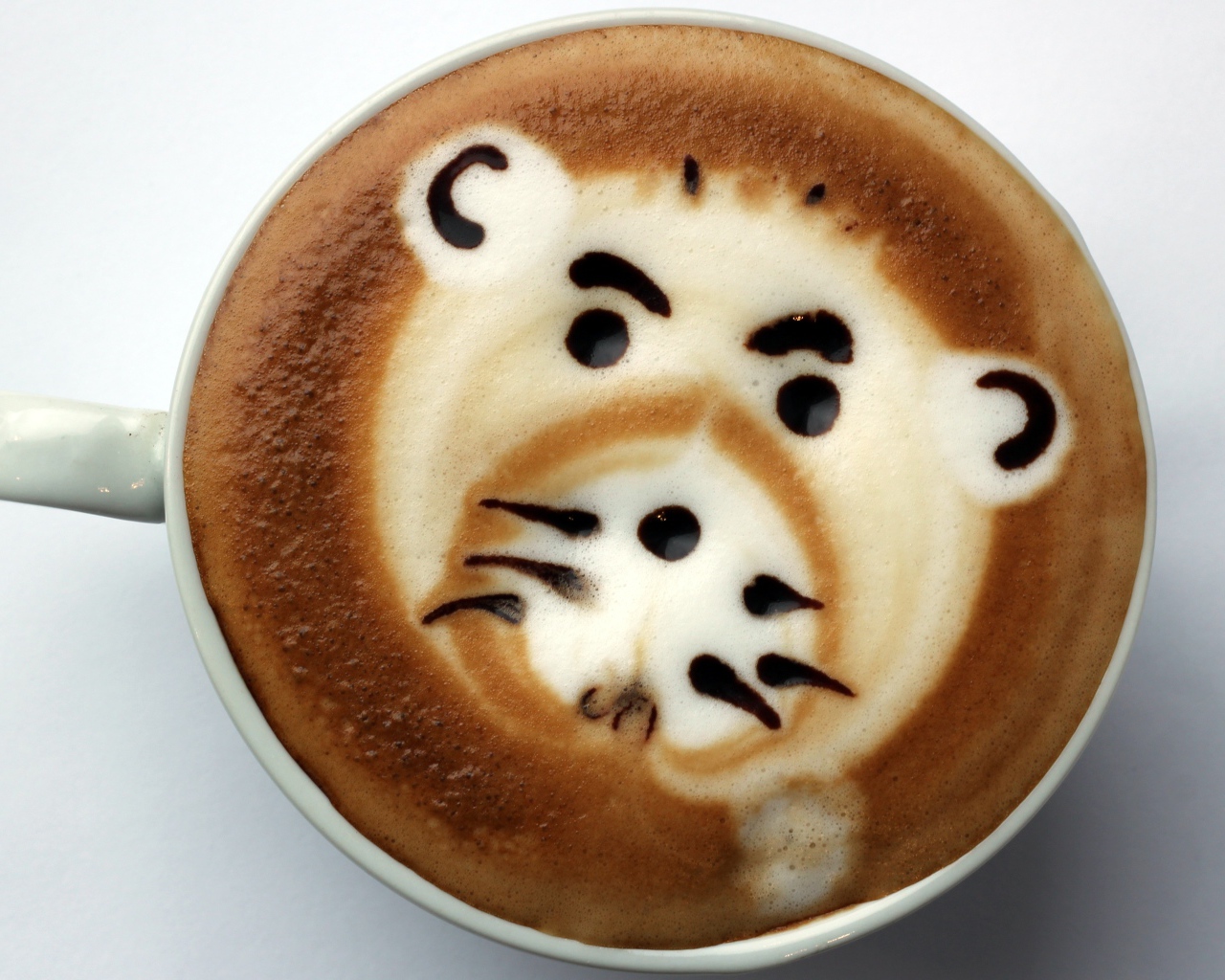 Белая чашка кофе с забавным рисунком на пене