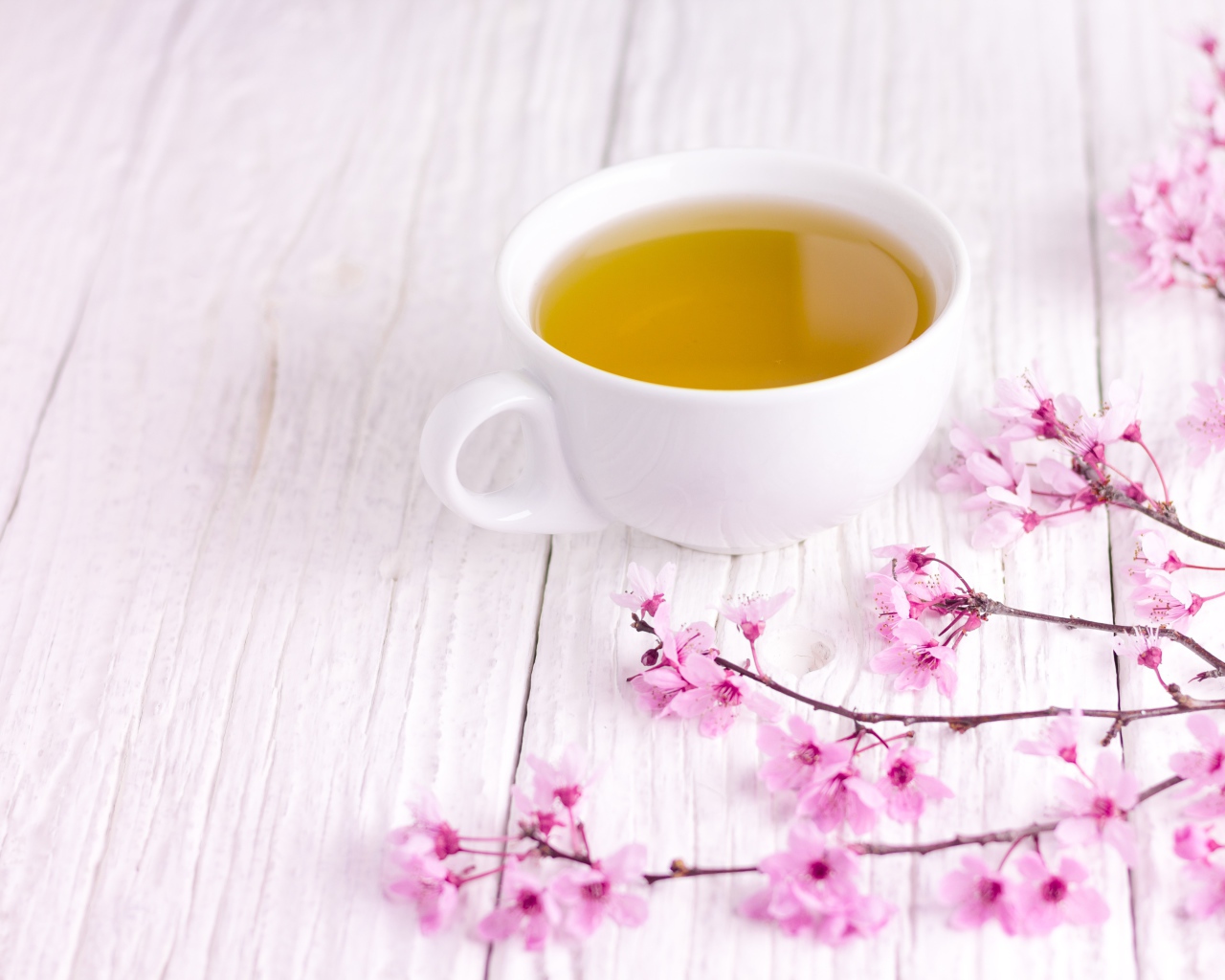 Белая чашка зеленого чая на столе с розовыми цветами