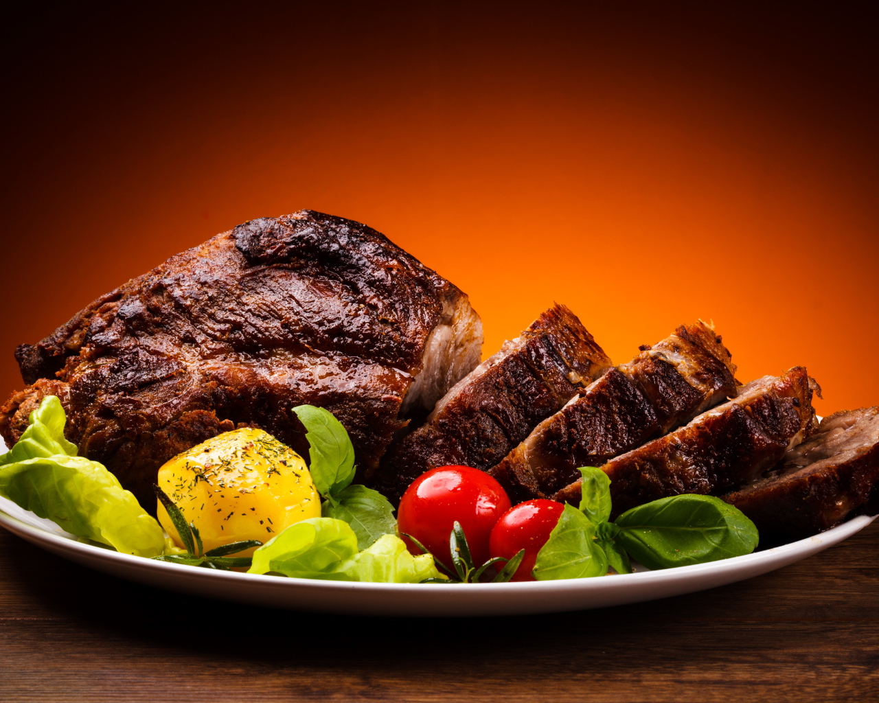 Кусок жареного мяса на тарелке с картофелем и помидорами 