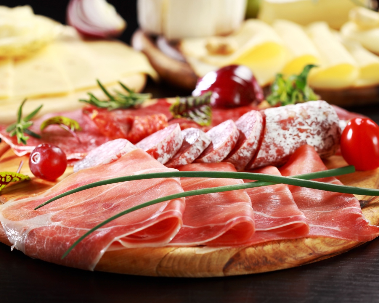 Аппетитная мясная нарезка на деревянной доске с зеленым луком