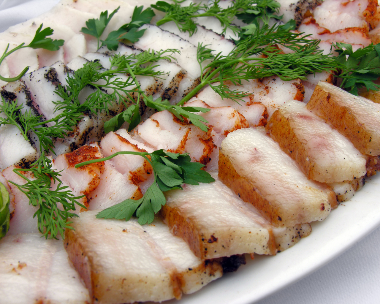 Аппетитное нарезанное копченое сало с зеленью 