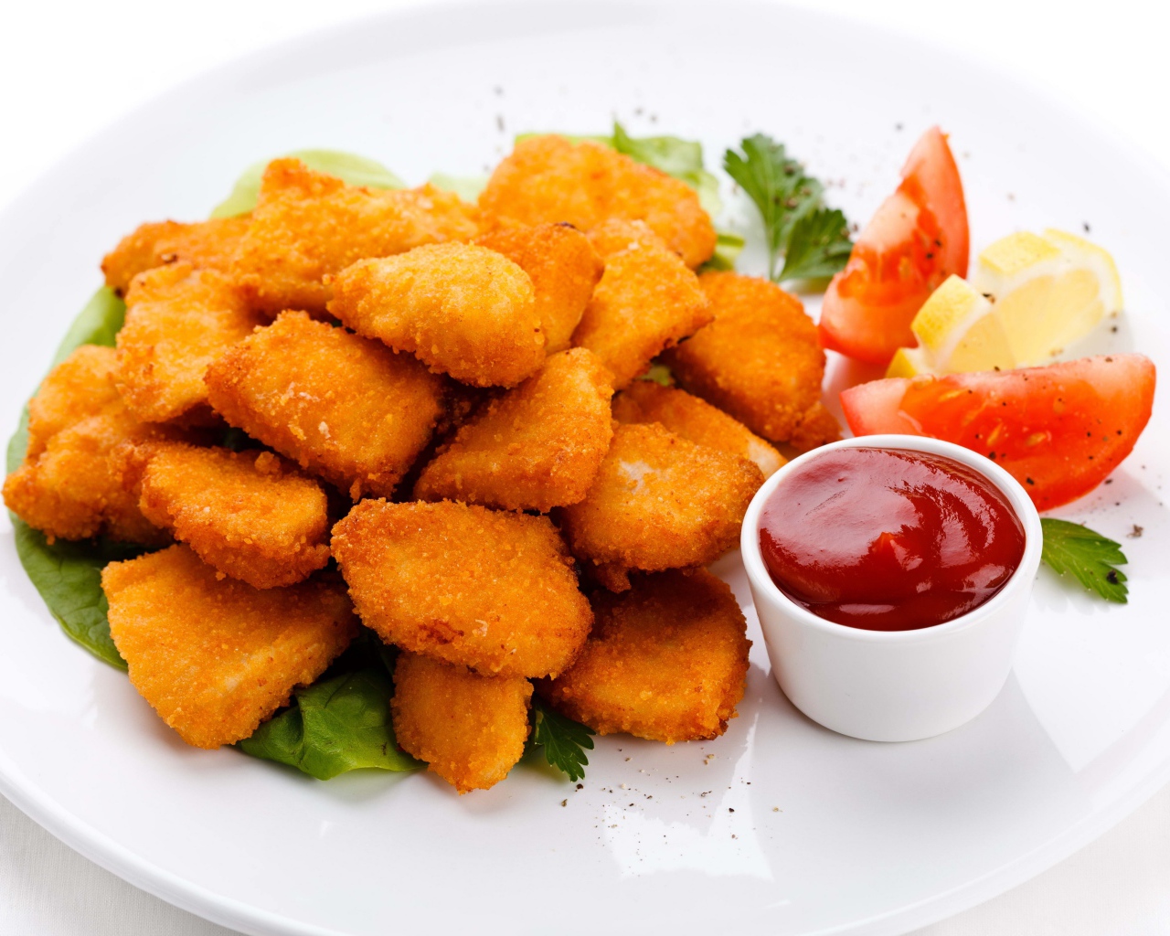 Куриные наггетсы с соусом и помидорами на белой тарелке 