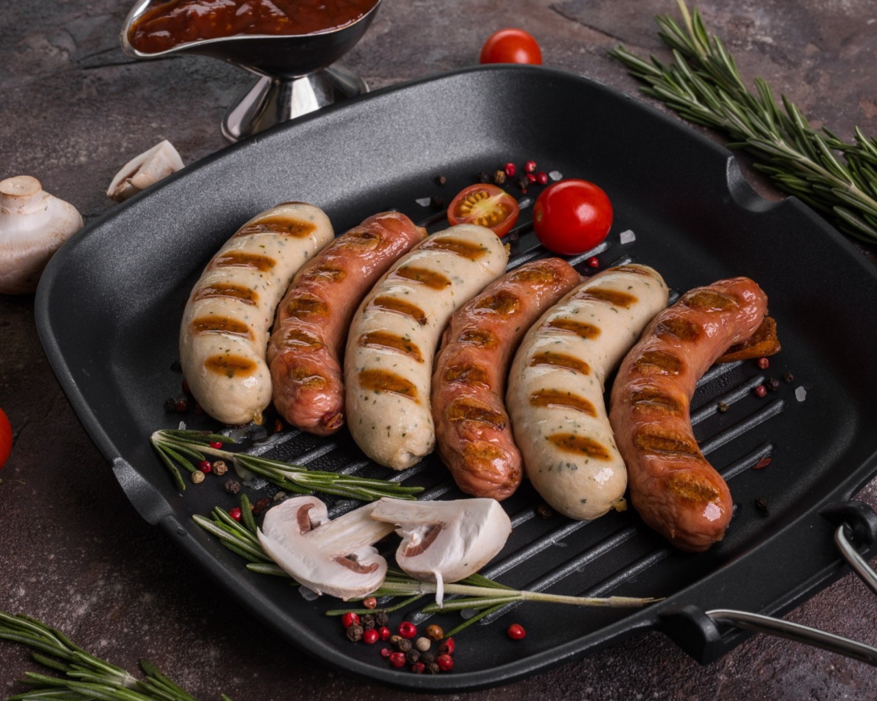 Колбаски гриль на столе с овощами 