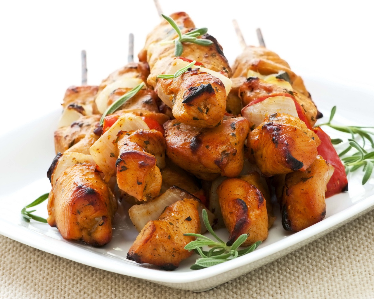 Шашлыки на белой тарелке с зеленью розмарина