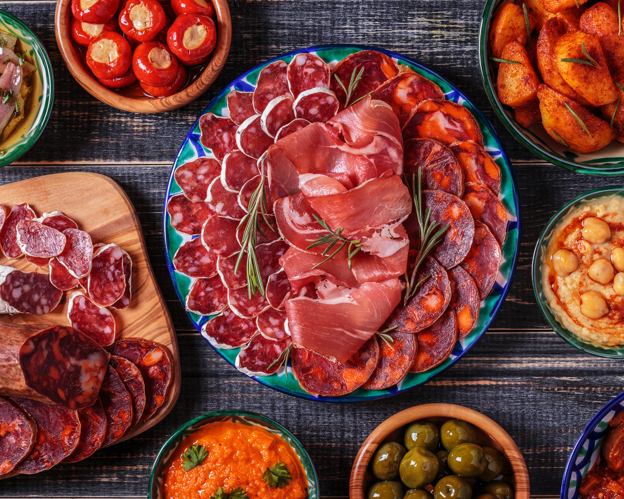 Большая тарелка с мясной нарезкой в центре праздничного стола