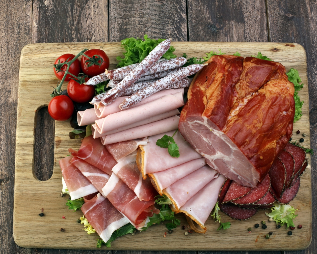 Мясная нарезка на разделочной доске с помидорами