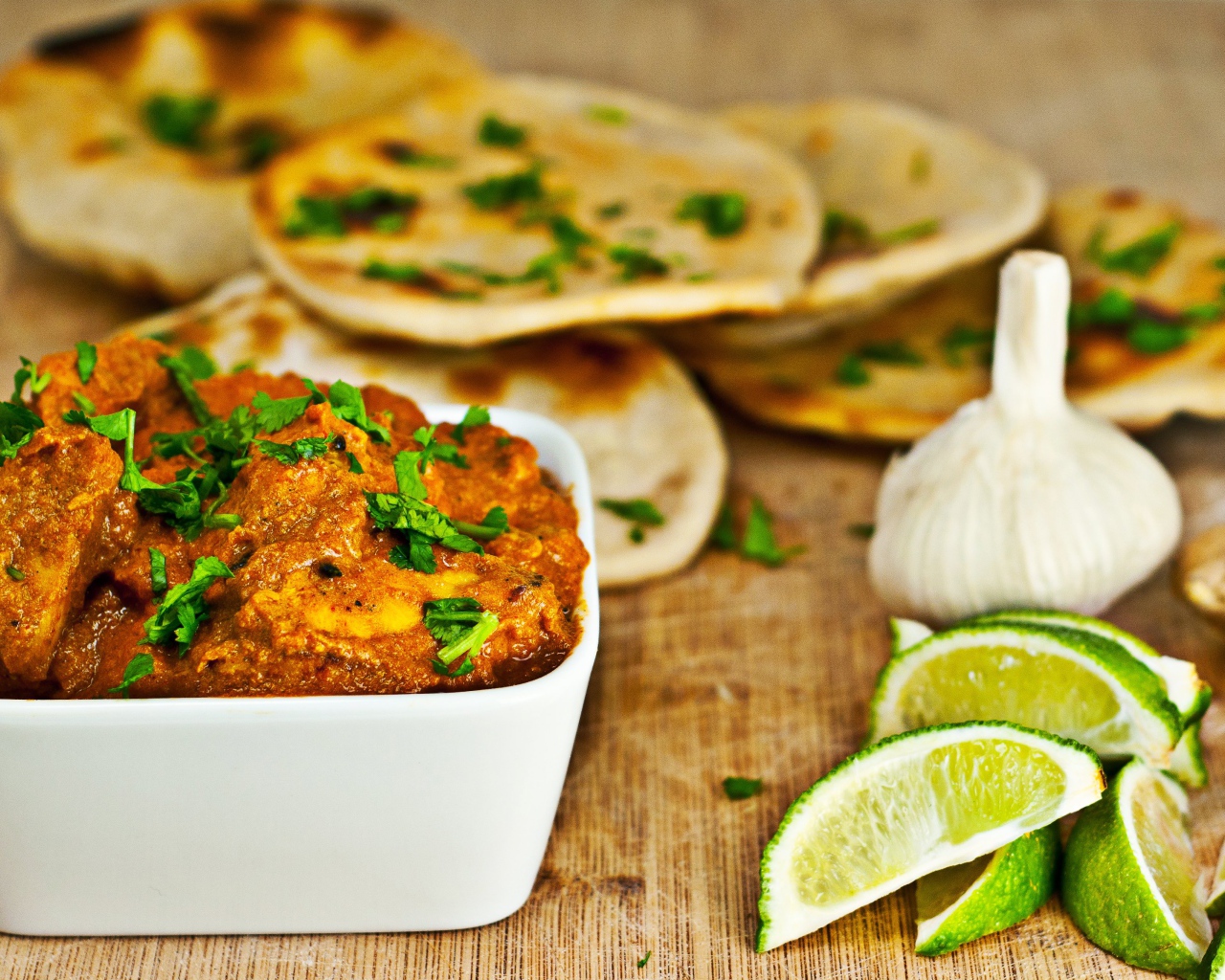 Мясное блюдо на столе с лепешками, кусочками лайма и чесноком