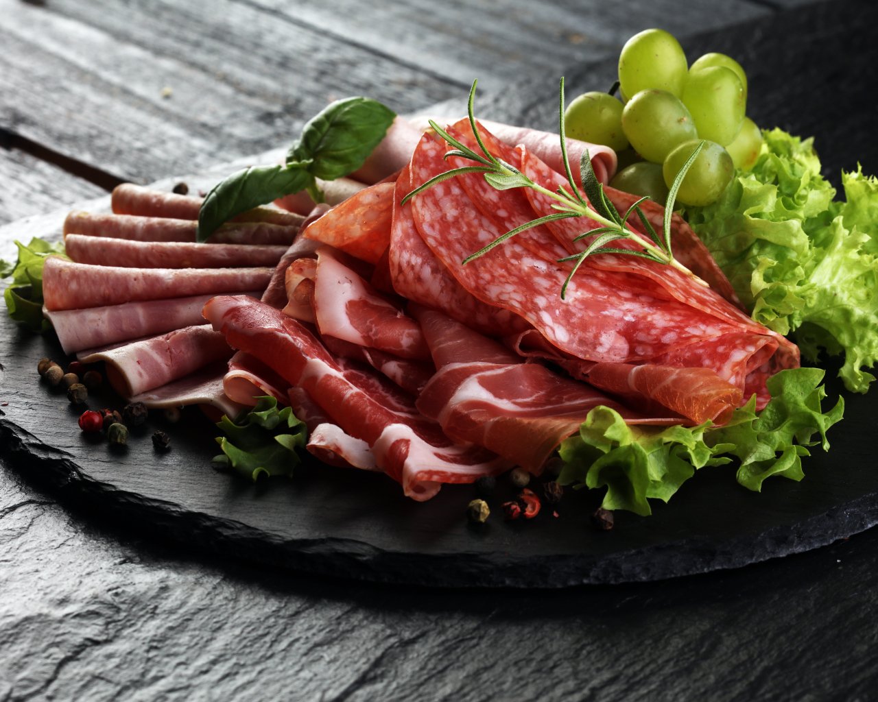 Мясная нарезка с листьями салата и белым виноградом 