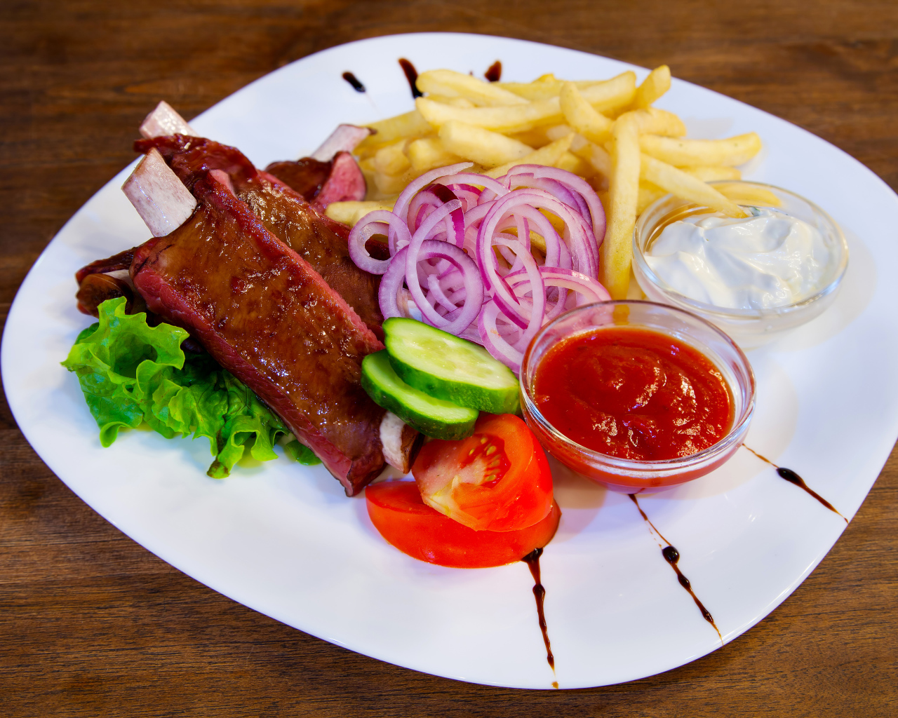 Мясо с овощами и картофелем фри на большой белой тарелке с соусом