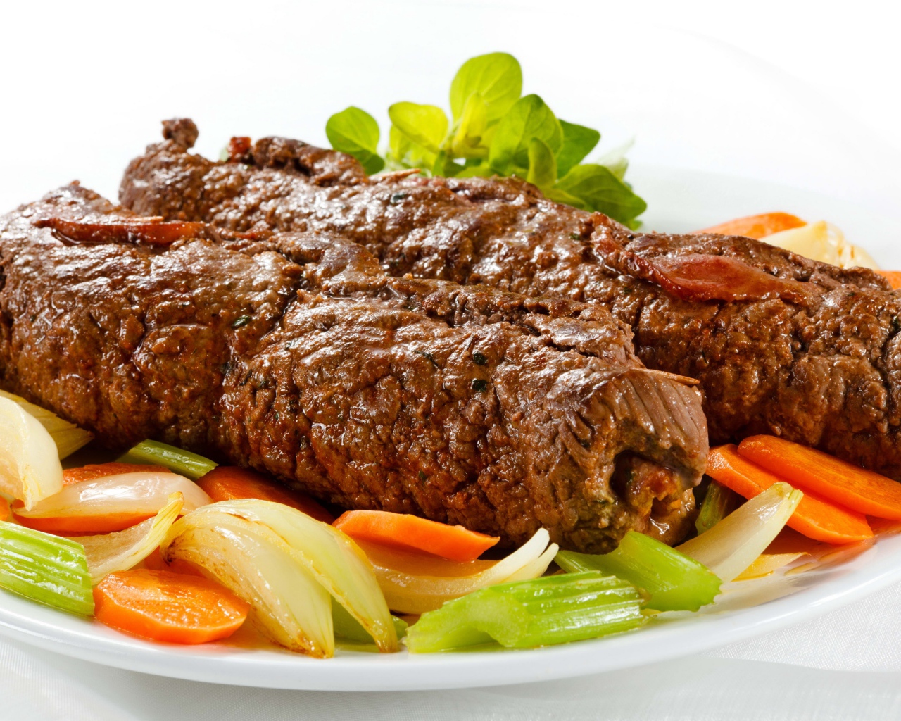 Свинина на тарелке с овощами на белом фоне