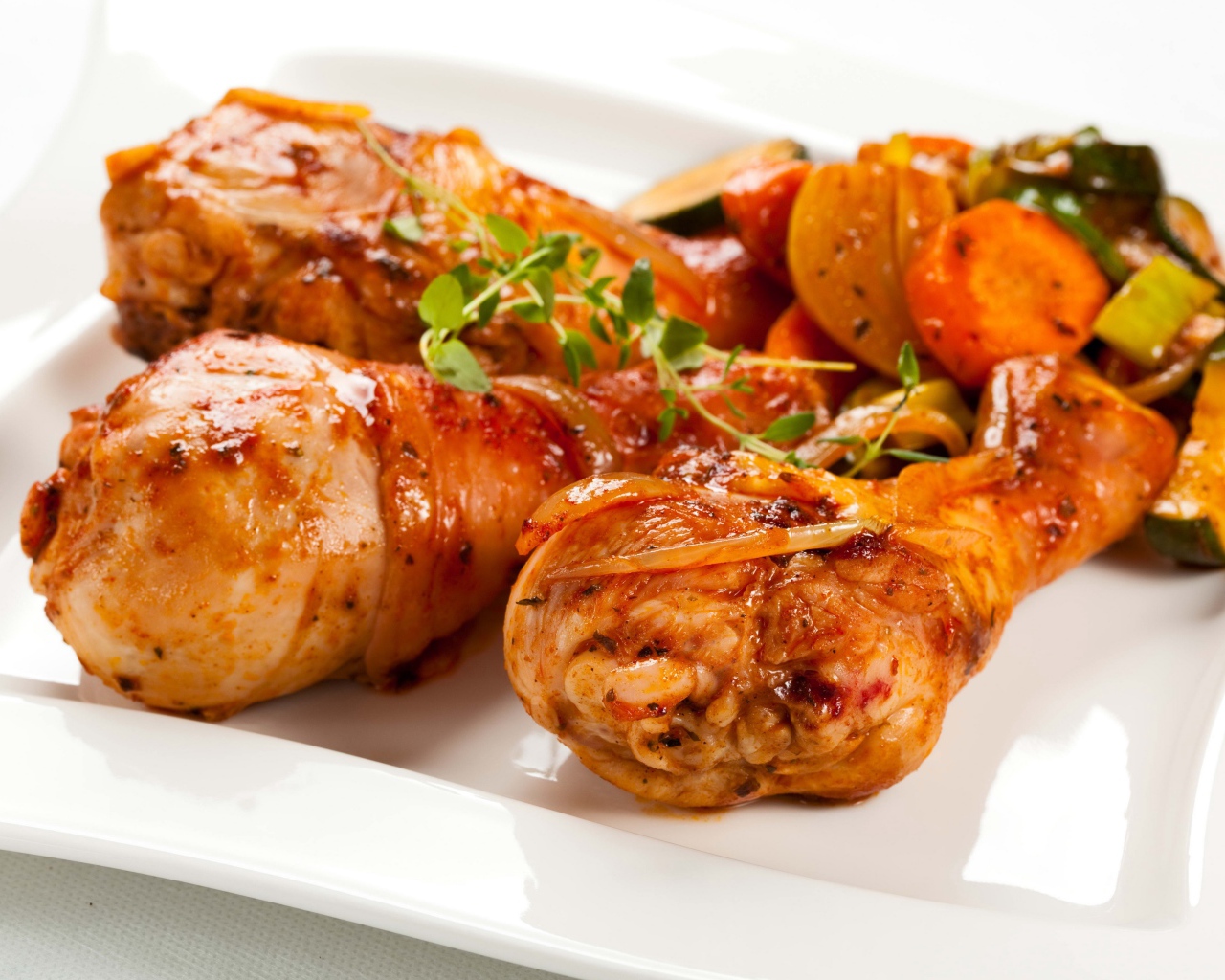Жареные куриные ножки с овощами на белом фоне