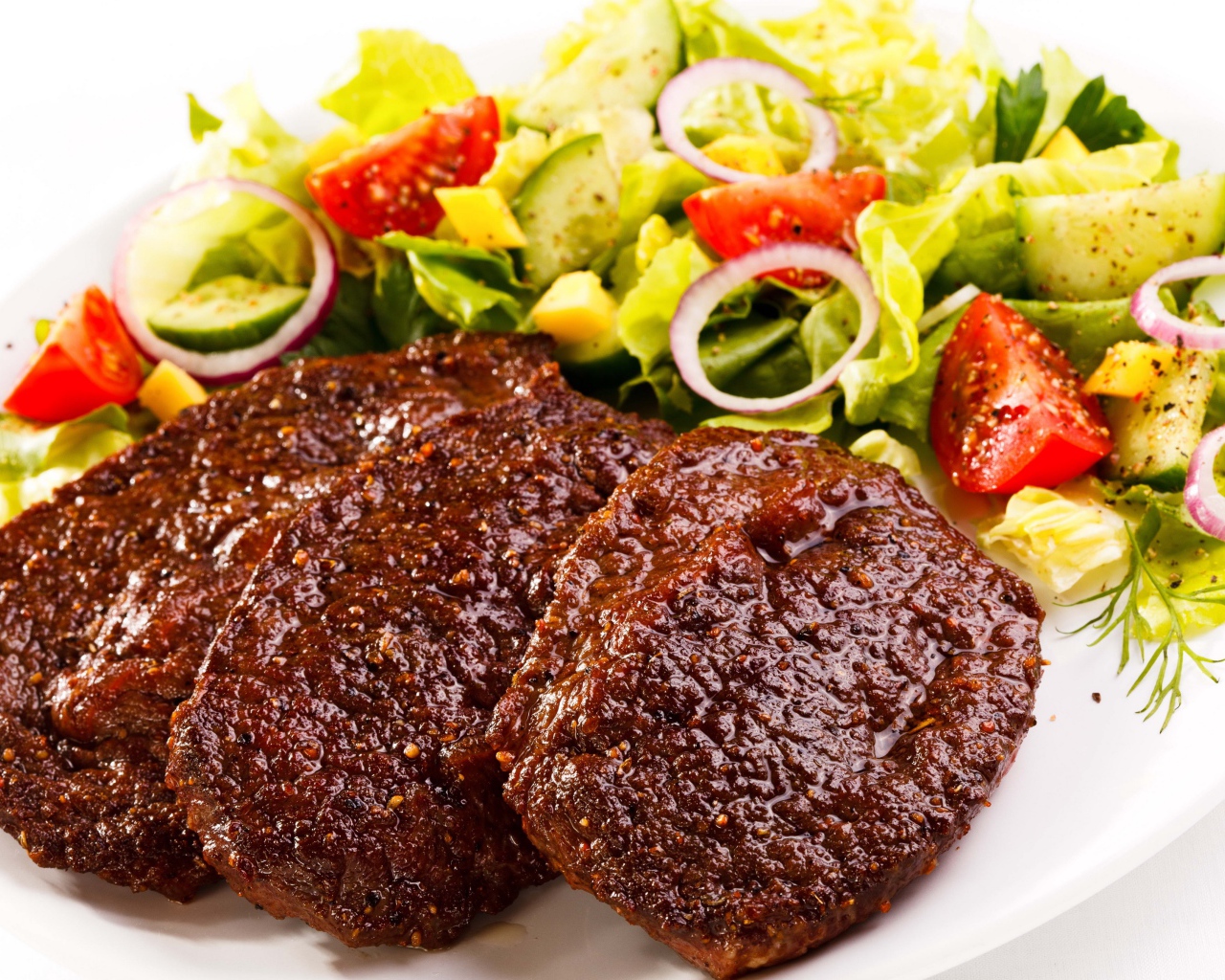 Три котлеты на тарелке с салатом на белом фоне