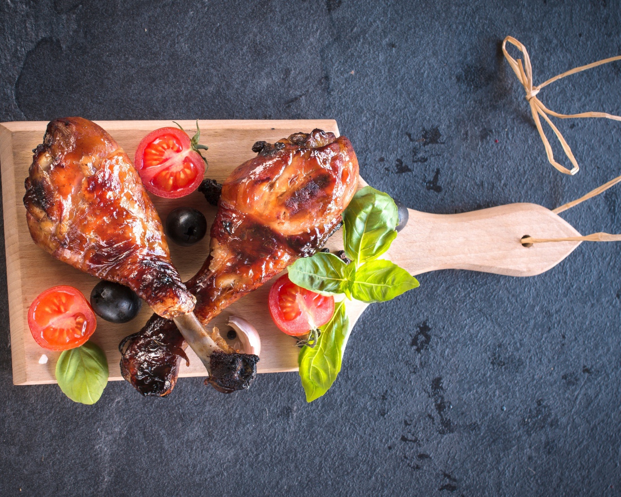 Две зажаренных куриных ножки с овощами на разделочной доске