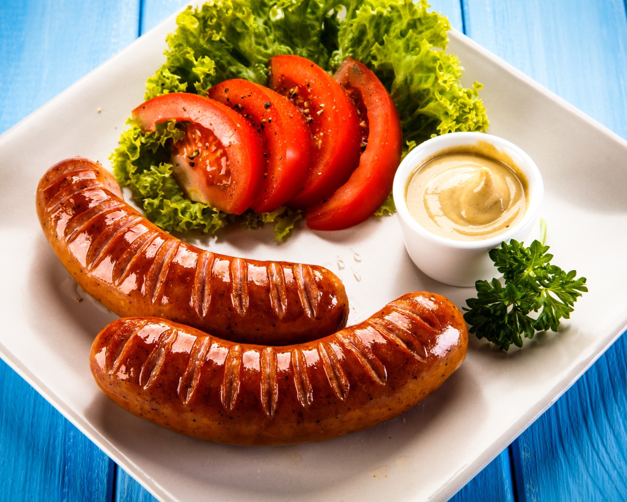 Две сосиски гриль на тарелке с овощами и горчицей