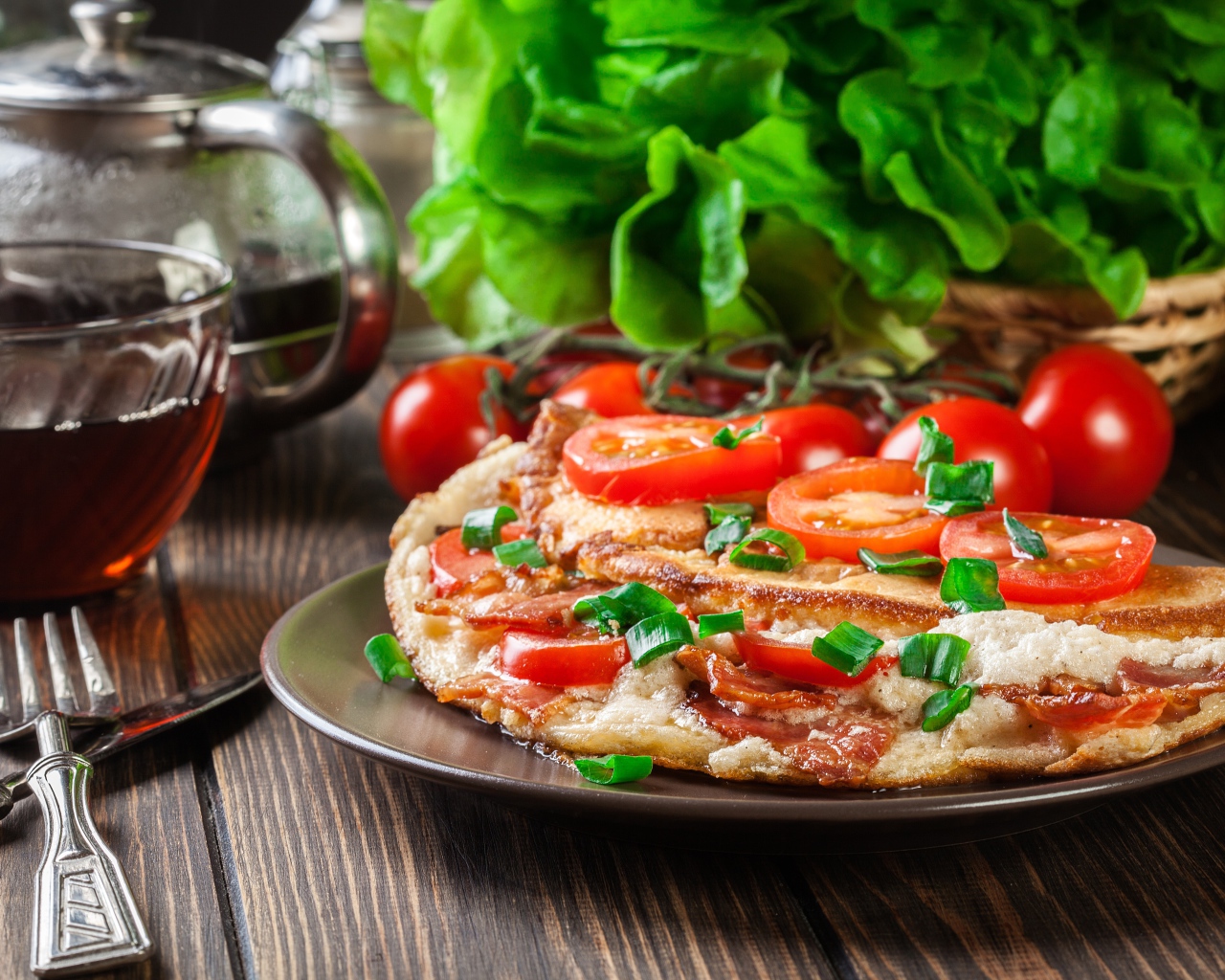 Пицца с помидорами на столе с чаем и зеленью 