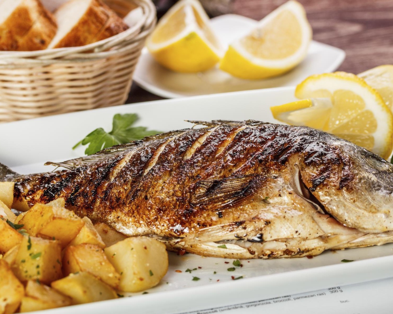 Запеченная рыба на тарелке с картофелем и лимоном 