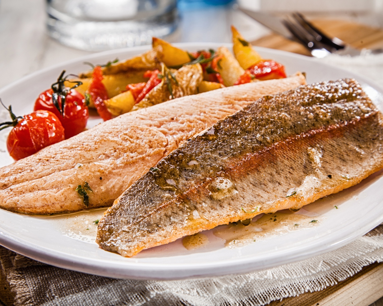Запеченная рыба с помидорами и овощами на белом блюде