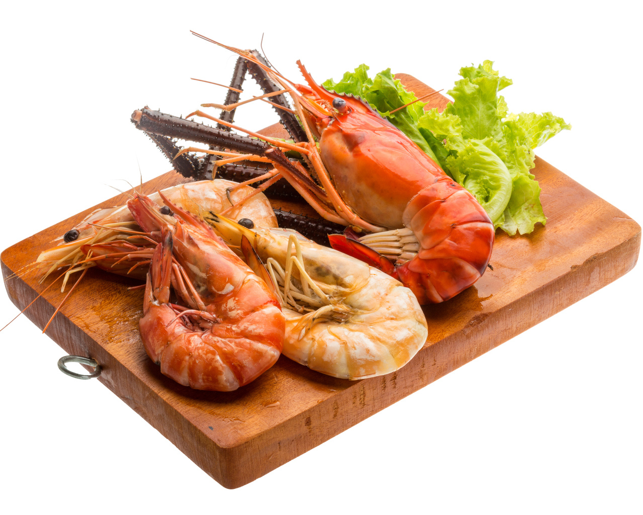 Вареные креветки с листьями салата на разделочной доске