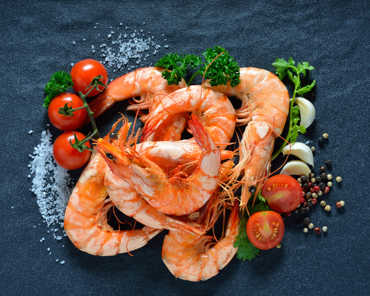 Вареные креветки на столе со специями и  помидорами 