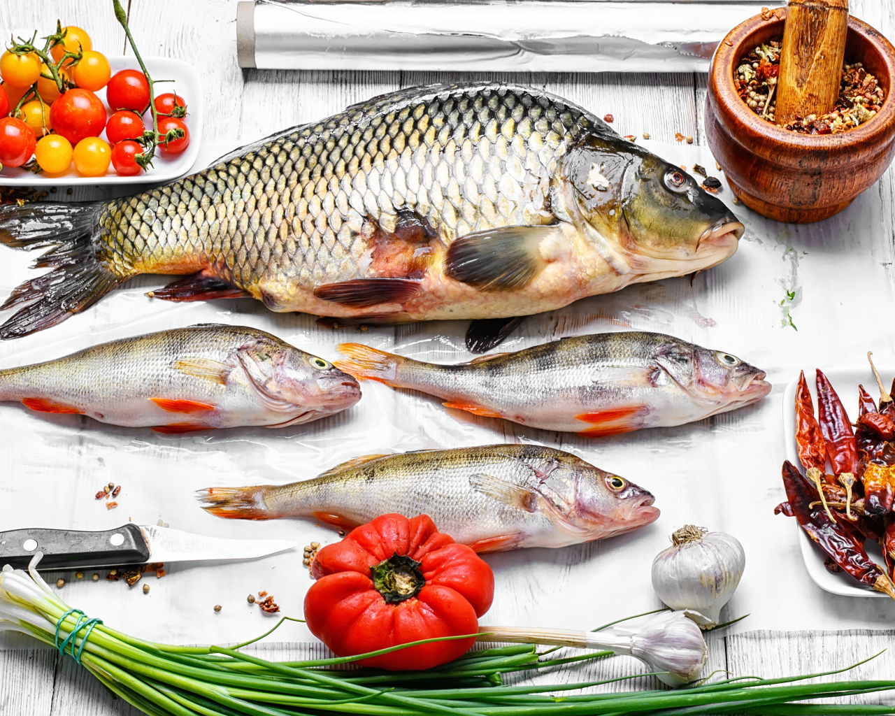 Свежая рыба на столе с помидорами, зеленым луком и  специями