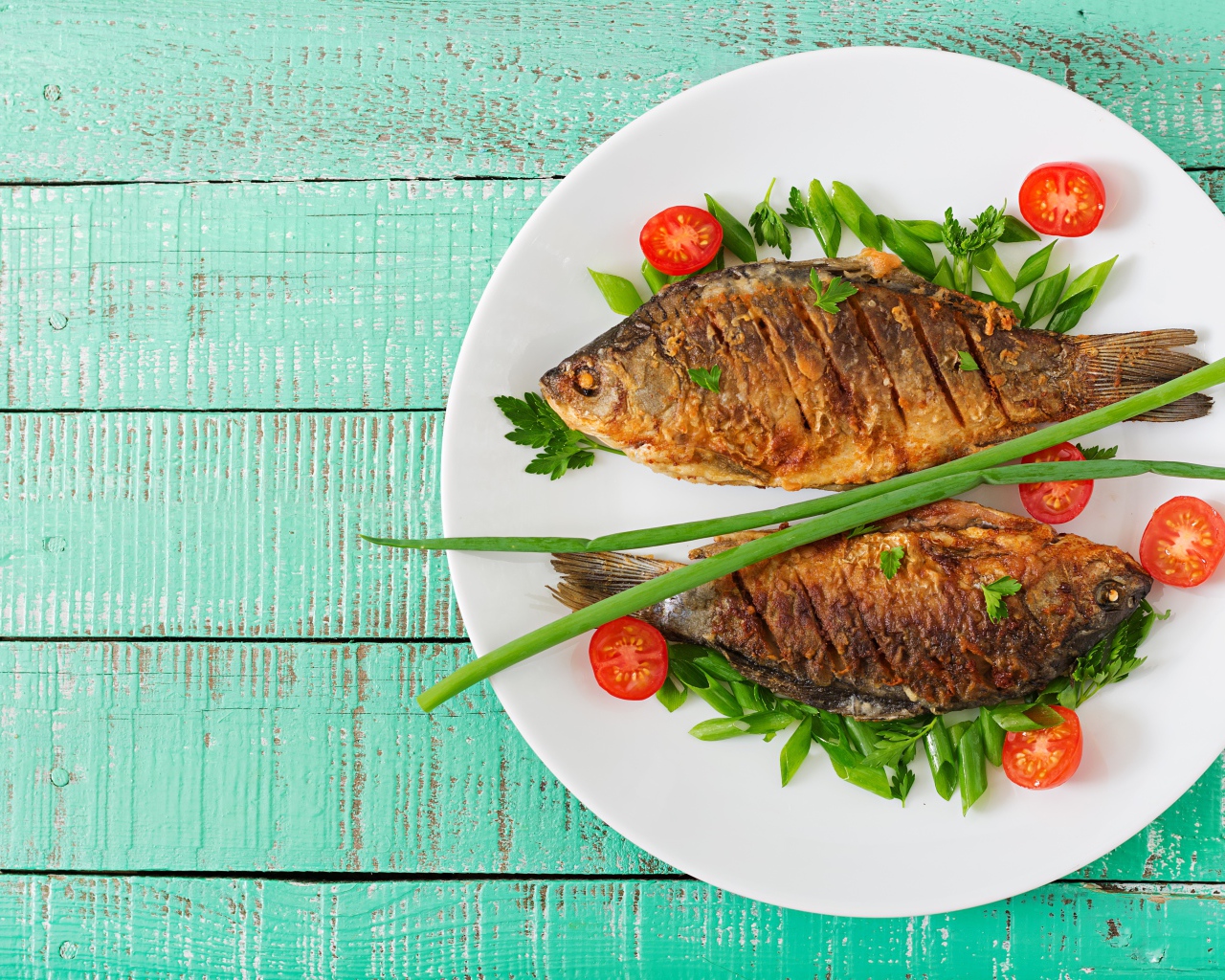 Fried fish with tomatoes and herbs on the table
