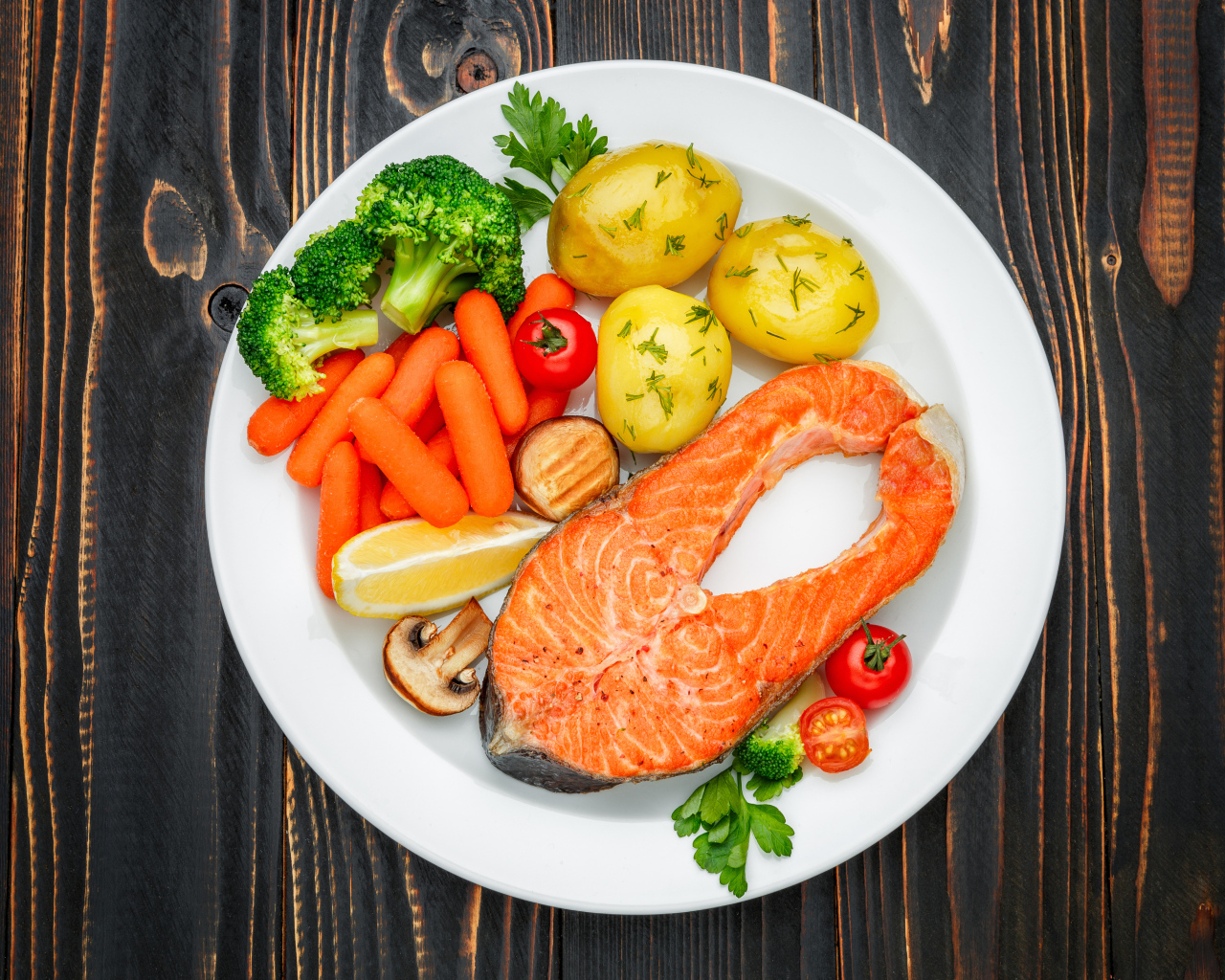 Красная рыба с овощами на белой тарелке на столе