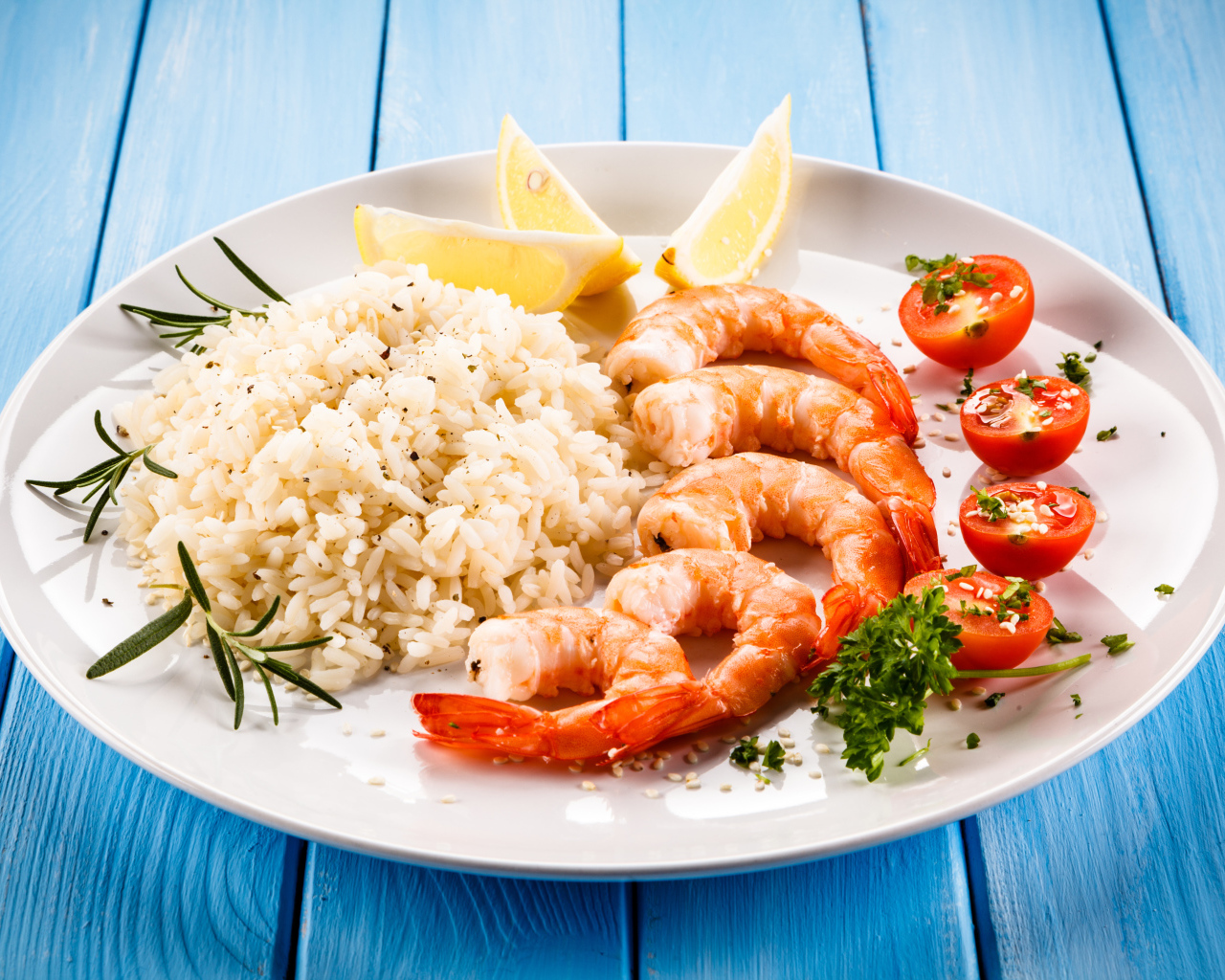 Креветки на тарелке с рисом, помидорами и лимоном