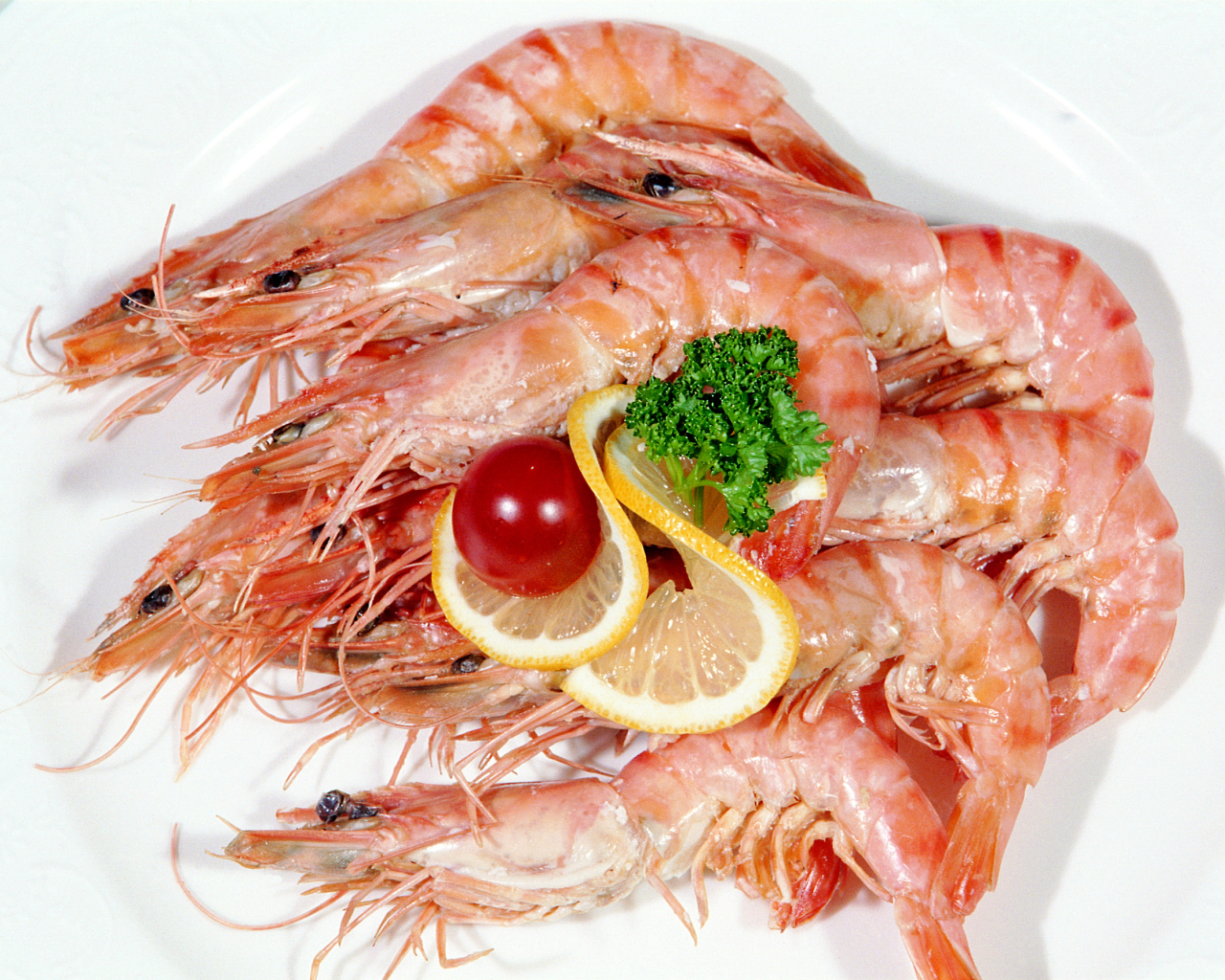 Креветки с лимоном и помидором на белой тарелке