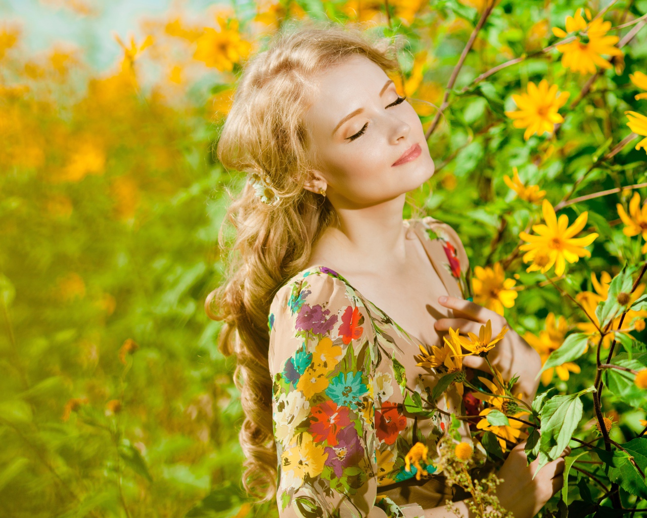 Красивая блондинка нежится в лучах солнца у желтых цветов