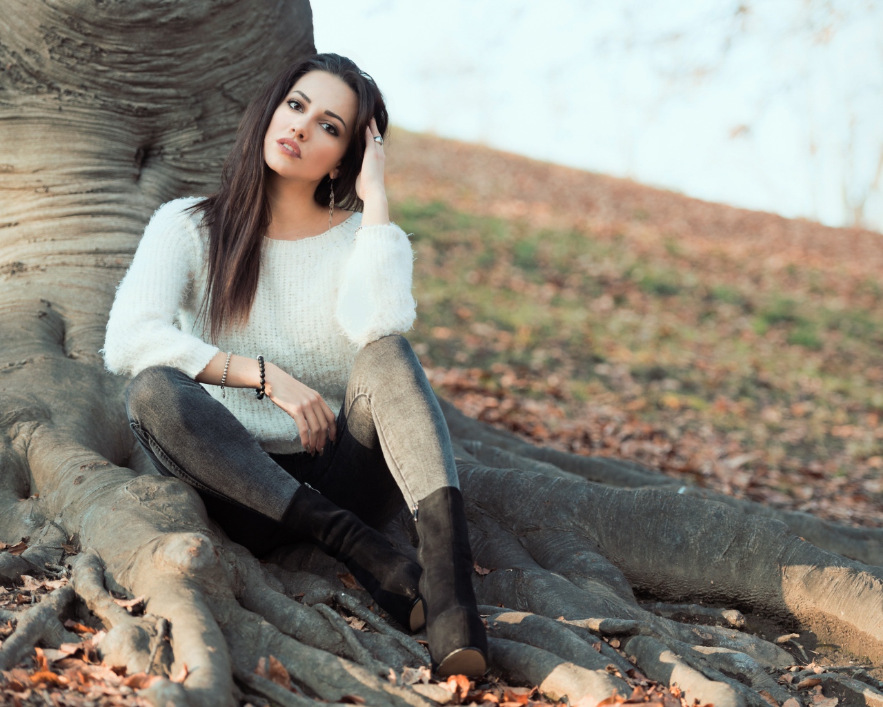 Красивая девушка сидит у дерева