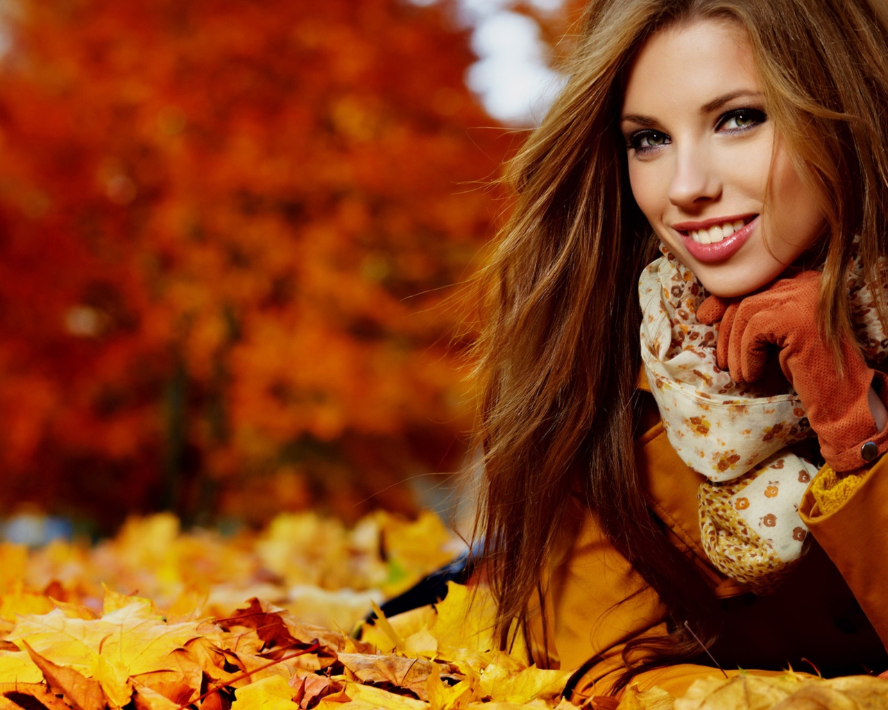 Красивая девушка лежит на опавших осенних листьях
